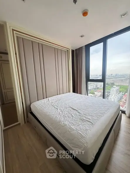 Modern bedroom with large window offering stunning city view