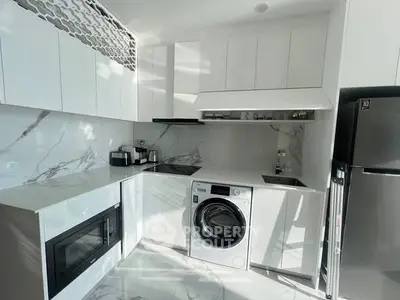 Modern kitchen with sleek white cabinetry, marble countertops, and built-in appliances including a washing machine.