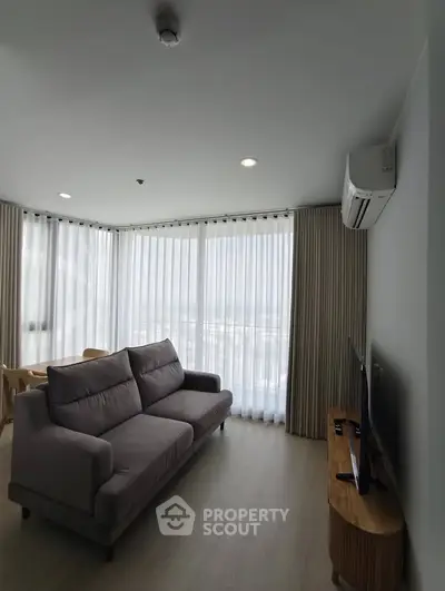 Modern living room with large windows and stylish furniture in a high-rise apartment.