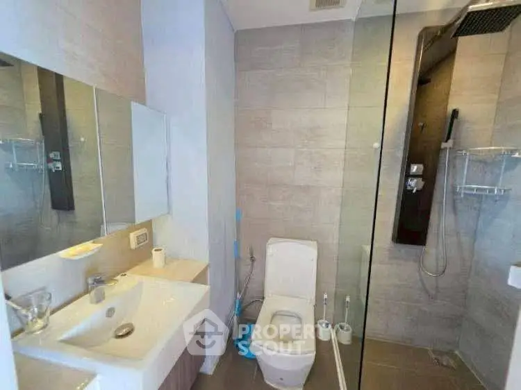 Modern bathroom with sleek fixtures and glass shower enclosure.