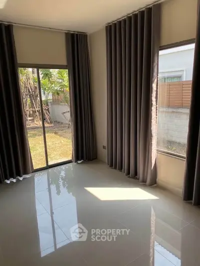 Bright room with large windows and garden view, featuring elegant curtains and glossy tiled floor.