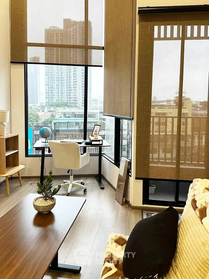 Modern living room with city view, featuring stylish furniture and large windows for natural light.