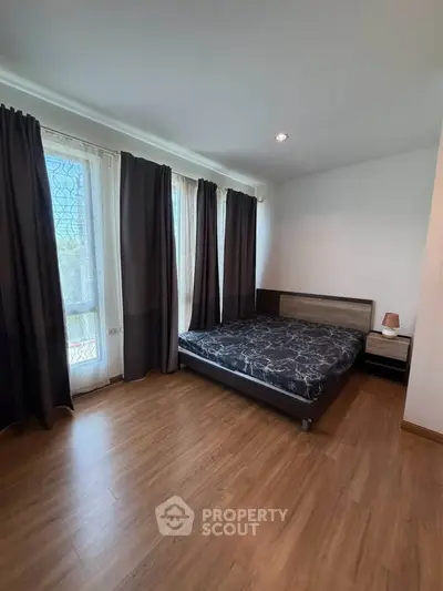 Spacious bedroom with large windows and modern decor in a cozy apartment.
