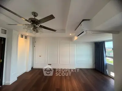 Spacious living room with elegant ceiling fan and large windows for natural light.