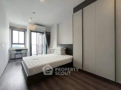 Modern bedroom with large window and sleek furniture in a high-rise apartment.