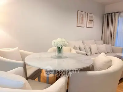 Elegant living room with white furniture and round marble table, perfect for modern living.