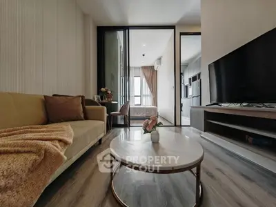 Modern living room with cozy sofa, marble coffee table, and large TV, leading to a stylish bedroom.