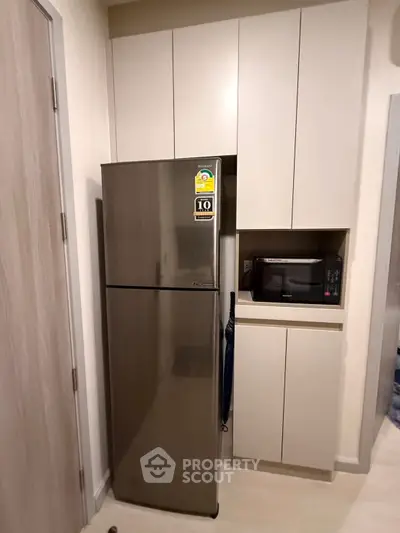 Modern kitchen with sleek fridge and built-in microwave in compact space.