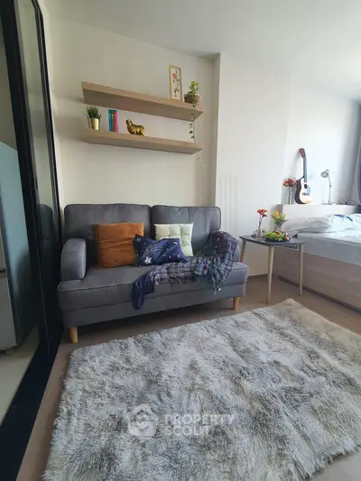 Cozy living room with plush rug, stylish sofa, and decorative shelves in modern apartment.
