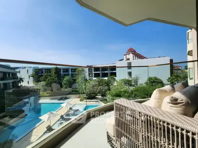 Luxurious balcony view overlooking a pristine pool and lush garden in a modern residential complex.
