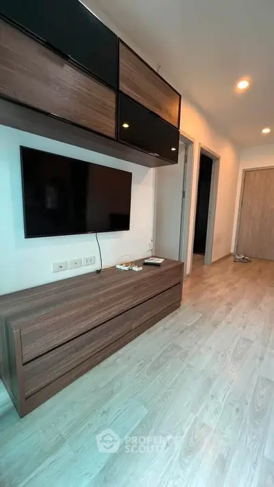 Modern living room with sleek wooden furniture and mounted TV, featuring stylish lighting and laminate flooring.