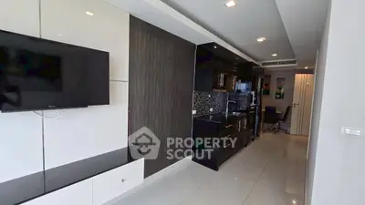 Modern kitchen with sleek black cabinets and wall-mounted TV in open layout apartment.