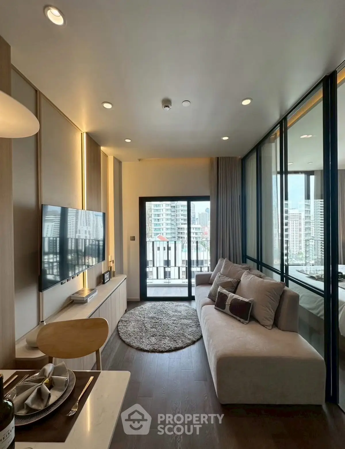 Modern living room with large windows and city view, featuring stylish decor and cozy seating area.
