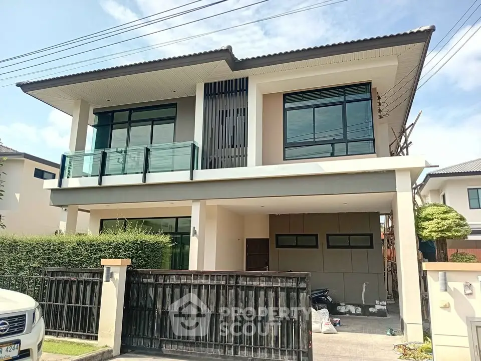 Modern two-story house with sleek design and spacious balcony in a suburban neighborhood.