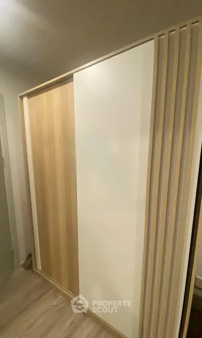 Modern wooden wardrobe with sliding doors in a stylish interior setting.