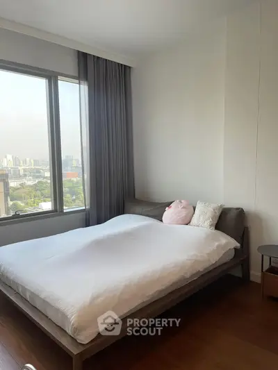 Modern bedroom with large window offering stunning city view, featuring cozy bed and elegant decor.