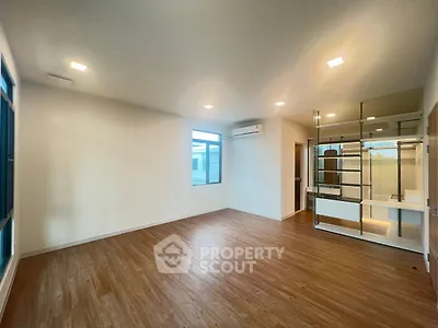 Spacious empty room with wooden flooring and large windows, ideal for customization.