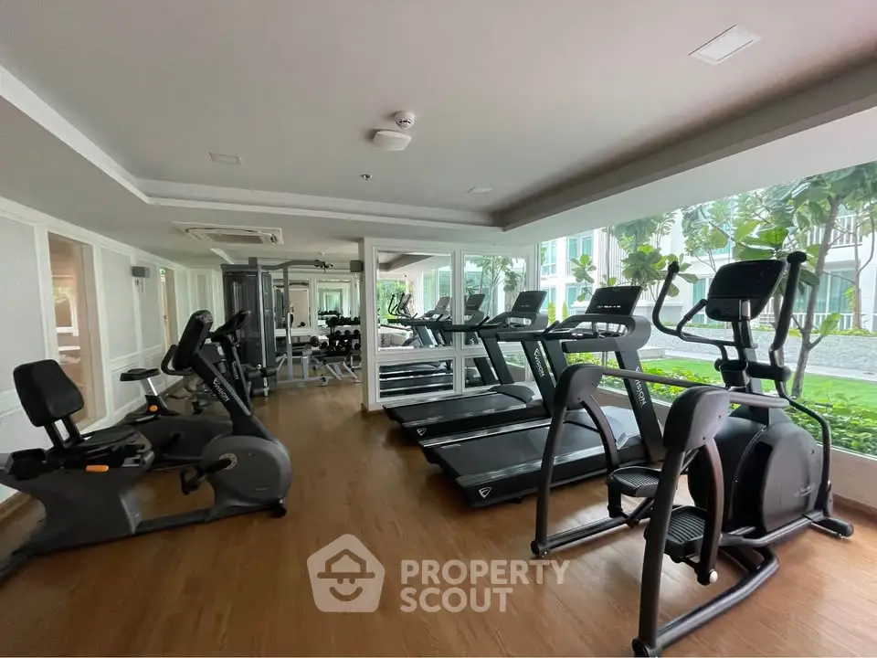 Modern gym with state-of-the-art equipment and large windows overlooking lush greenery.
