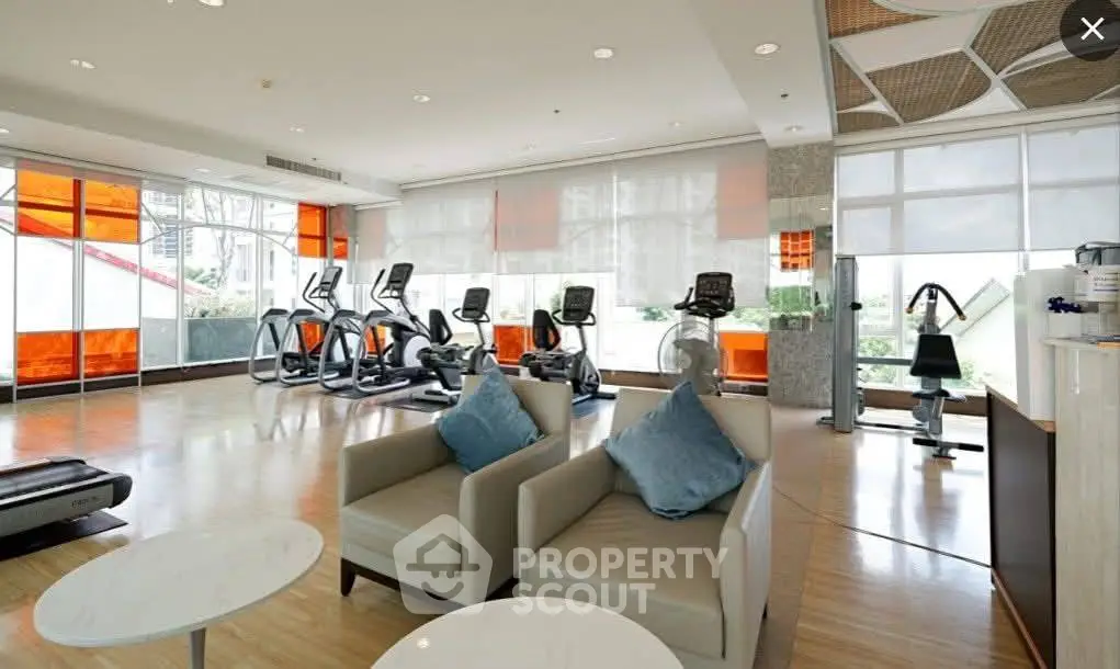 Spacious modern gym with state-of-the-art equipment and stylish seating area.