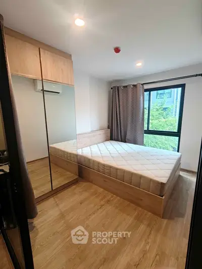 Modern bedroom with wooden flooring, mirrored wardrobe, and large window with a view.