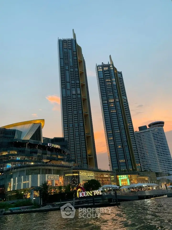 Stunning view of modern skyscrapers at sunset with vibrant city lights reflecting on the river.