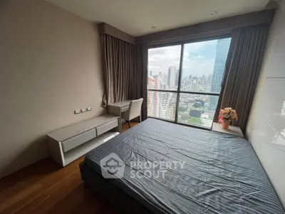 Modern bedroom with city view, featuring large window and sleek furnishings.