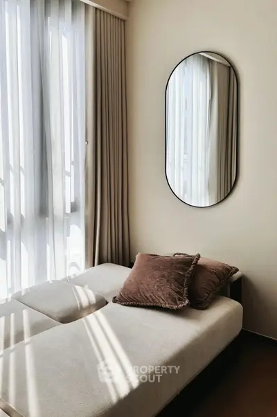 Cozy bedroom with elegant decor and natural light through sheer curtains.