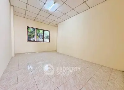 Spacious empty room with tiled floor and large window, ideal for customization.