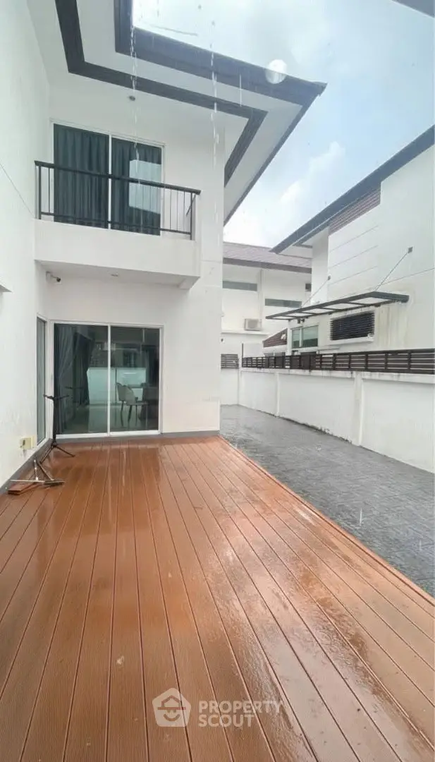 Modern house exterior with spacious wooden deck and balcony, perfect for outdoor relaxation.