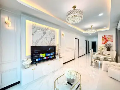 Luxurious modern living room with elegant decor and dining area, featuring marble accents and stylish lighting.