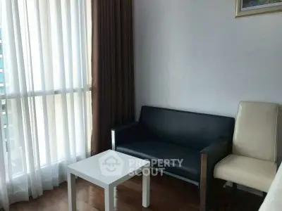 Cozy living room with modern furniture and large window with curtains.