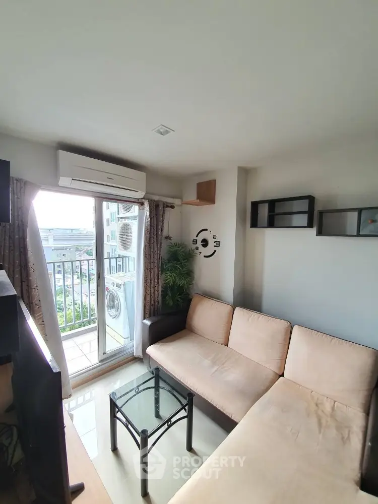 Cozy living room with balcony view, modern sofa, and wall clock, perfect for urban living.
