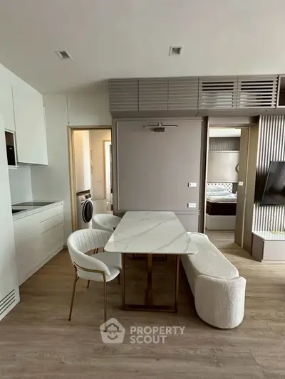 Modern open-plan living space with sleek kitchen and stylish dining area, featuring contemporary furniture and neutral tones.