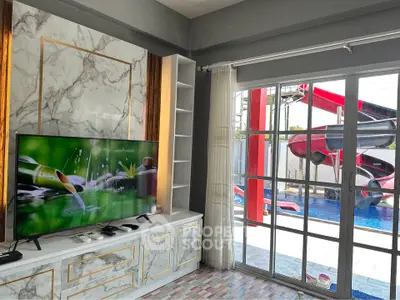 Luxurious living room with marble accents and poolside view, featuring a large TV and elegant decor.