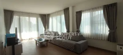 Spacious living room with large windows and modern furniture, perfect for relaxation.