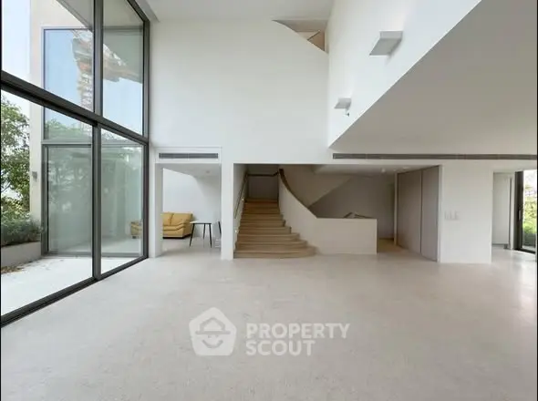 Spacious modern living room with large windows and elegant staircase