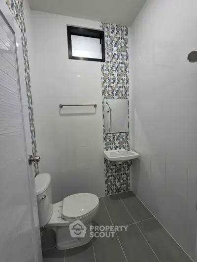 Modern bathroom with sleek design, featuring a toilet, sink, and stylish tiled wall accents.