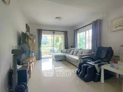Spacious living room with modern decor and large windows offering natural light and garden view.