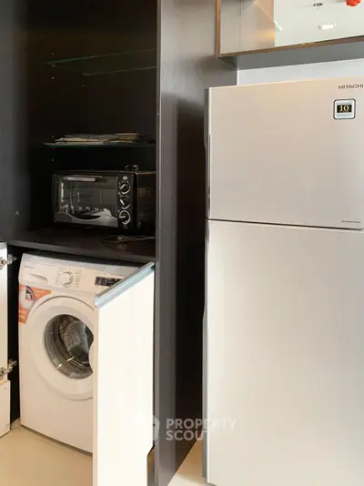 Modern kitchen with washing machine, oven, and fridge in sleek cabinetry.