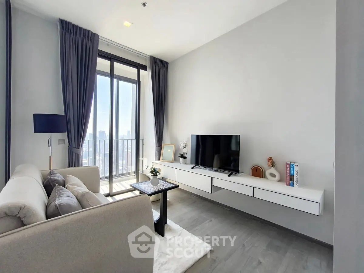 Modern living room with sleek furniture and large windows offering city views.