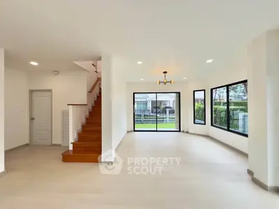 Spacious modern living room with large windows and wooden staircase