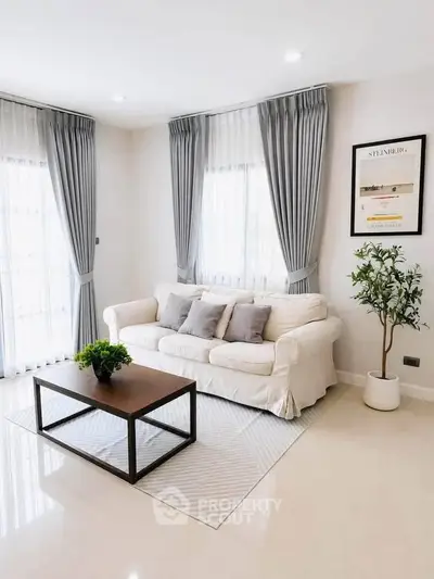 Elegant living room with white sofa, modern coffee table, and stylish decor in bright natural light.