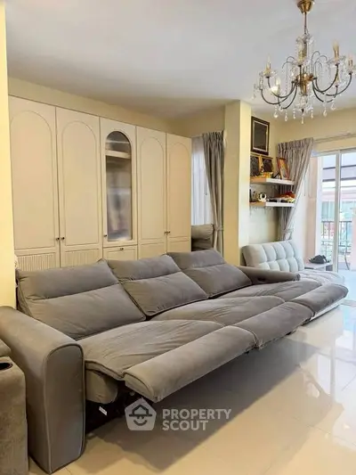 Spacious living room with elegant chandelier and modern gray sofa, perfect for relaxation and entertaining.