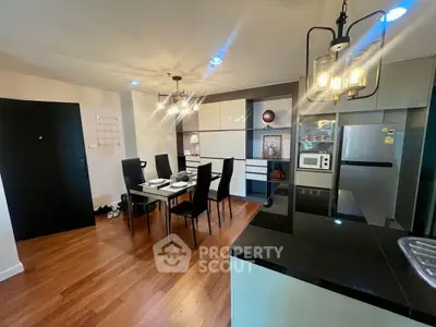 Modern open-layout kitchen and dining area with sleek black countertops and elegant lighting.