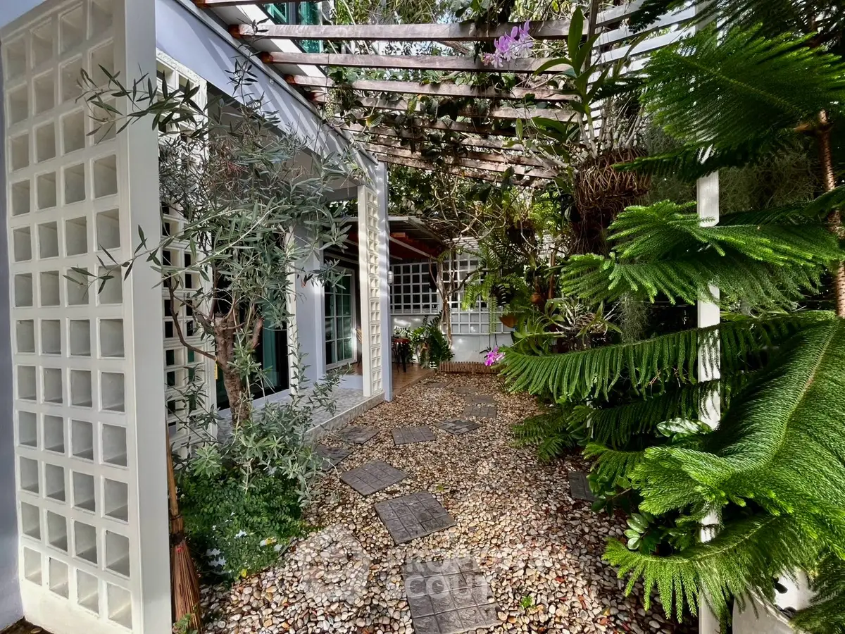 Charming garden pathway with lush greenery and modern trellis design, perfect for tranquil outdoor living.