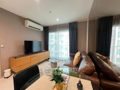 Modern living room with leather sofa, TV, and large windows in a stylish apartment.