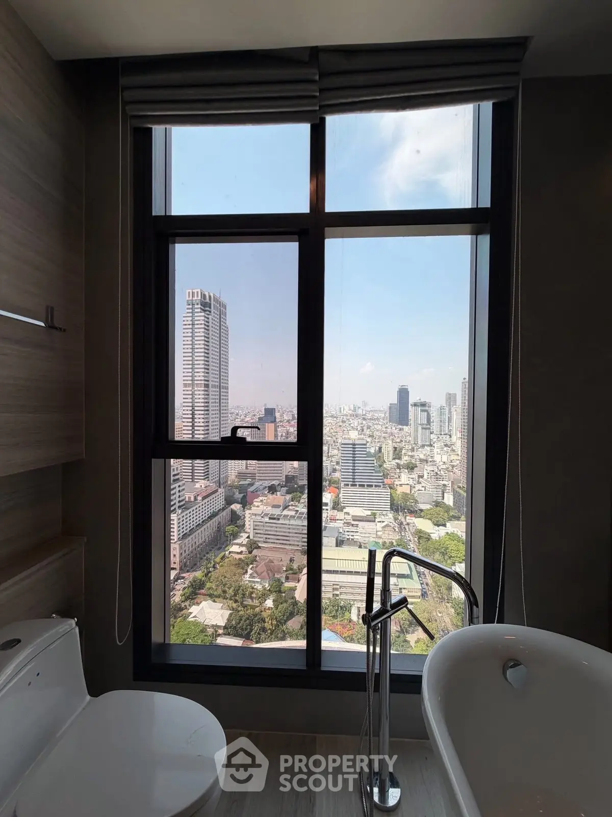 Luxurious bathroom with stunning city view from high-rise window, featuring modern bathtub and sleek design.