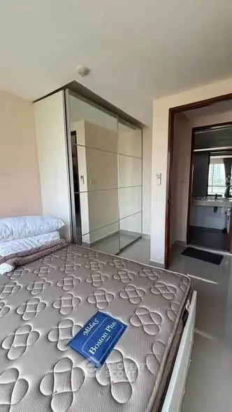 Modern bedroom with large mirrored closet and ensuite bathroom in high-rise apartment.