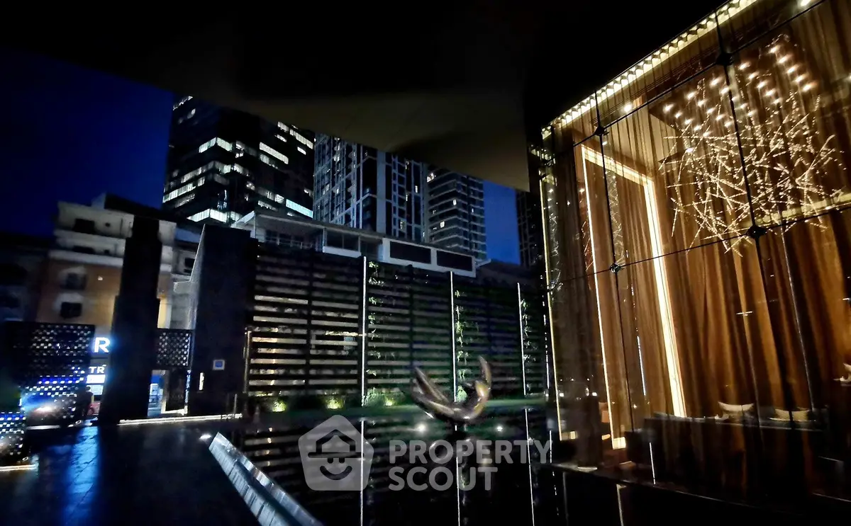Luxurious modern building exterior with stunning night lighting and water feature, showcasing urban elegance.
