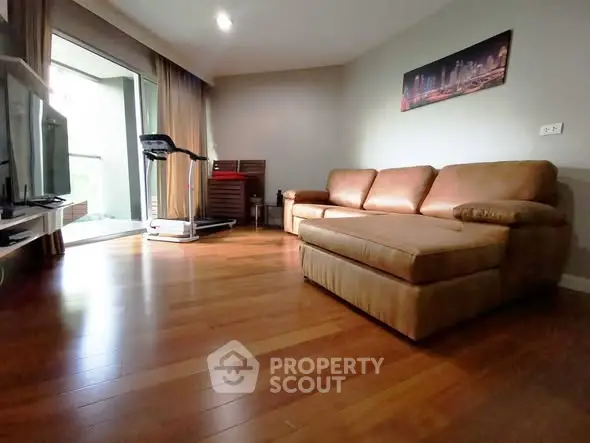 Spacious living room with hardwood floors and cozy leather sofa